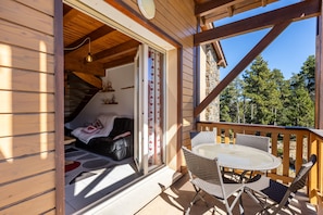 Eine Holzhütte mit Balkon, Esstisch und einer Couch.
