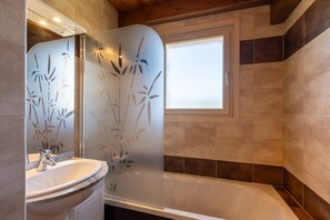 A bathroom with a bathtub, a sink, and a mirror. - Douce Altitude - Station de ski accessible à pied (Bolquère)