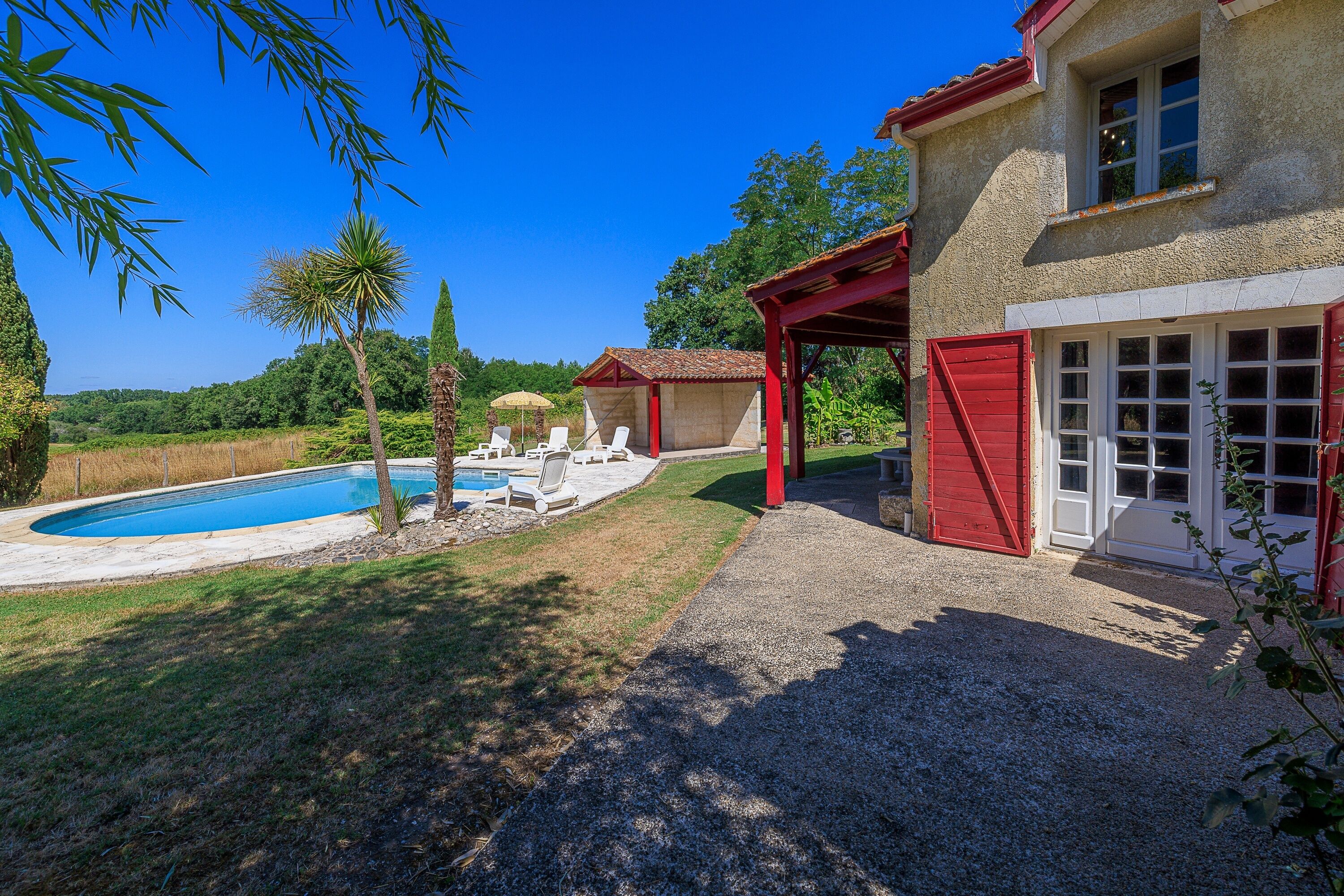 Una casa con piscina, mobiliario exterior y un patio cubierto.