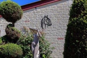 Un muro de piedra con una escultura de caballo y un árbol pequeño.