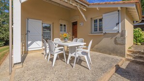 A covered patio with a table and chairs, a door, and a window with shutters. - Le Colombier de Sauvignac - Avec piscine privée (Sauvignac)