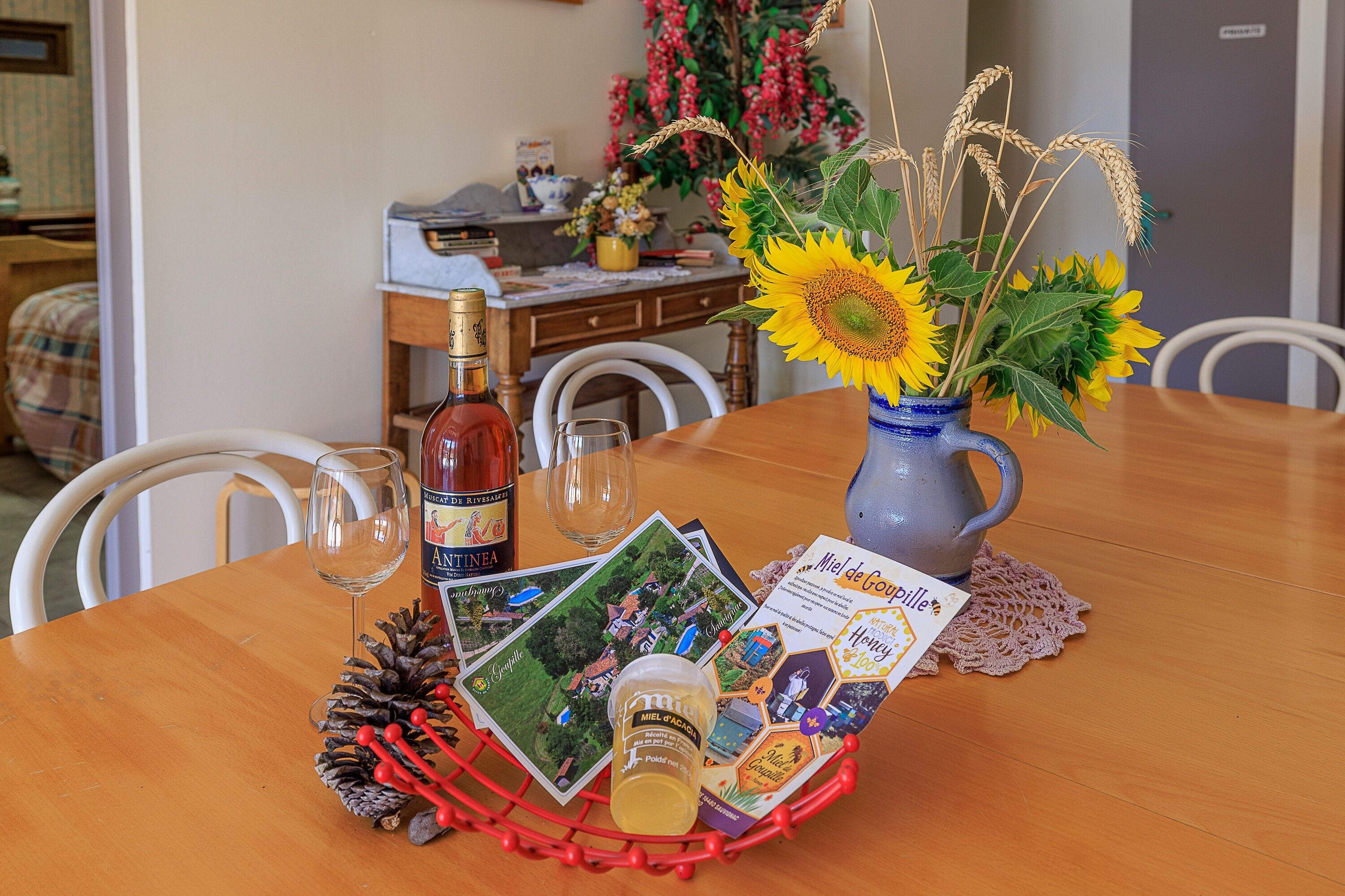 Una mesa de comedor con una botella, una copa de vino y un florero con girasoles.