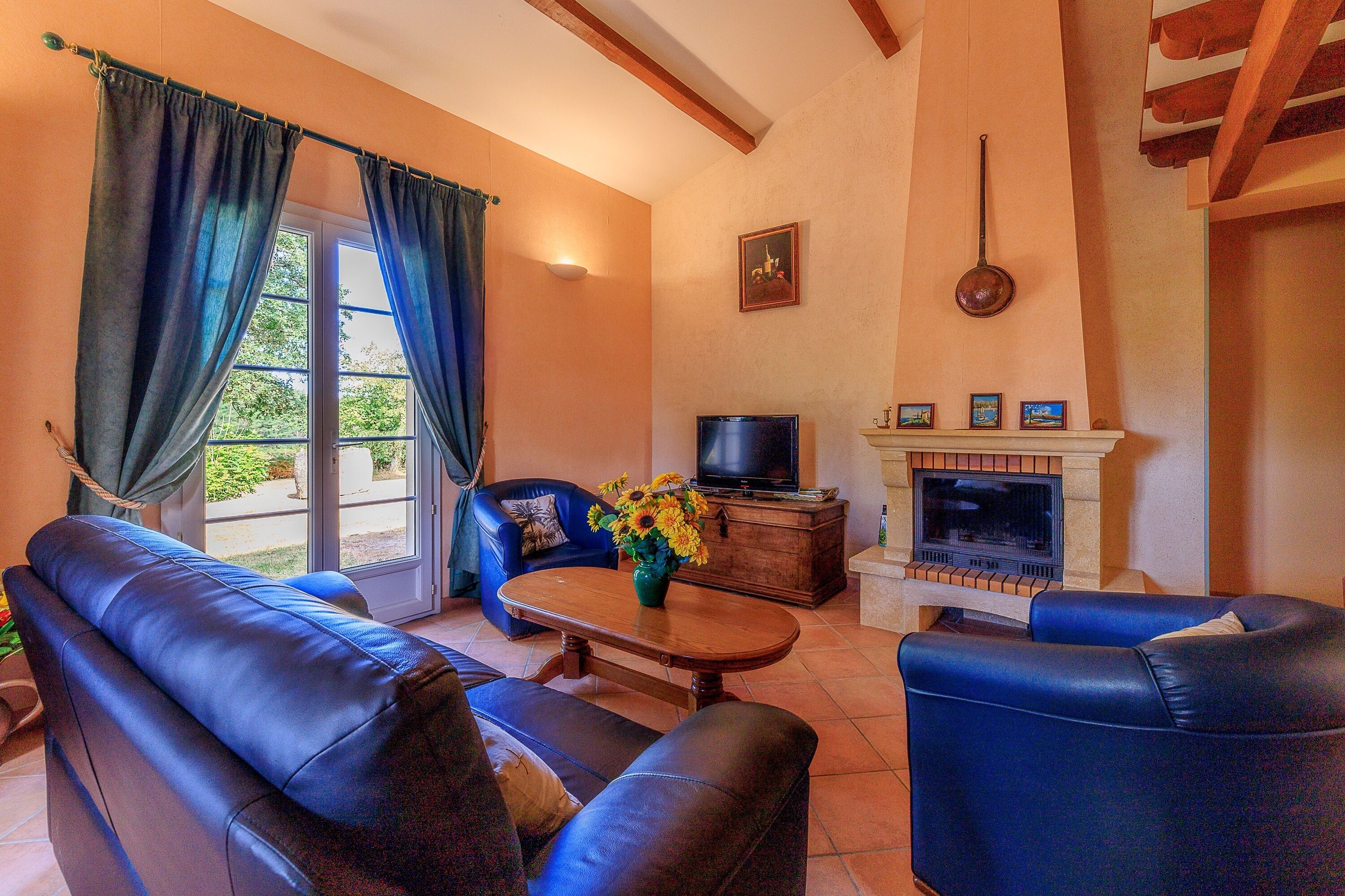 Una sala de estar con un sofá, un sillón azul, un televisor y una chimenea.