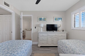 A bedroom with two beds, a TV, a dresser, and a window with shutters. - ⛱️Beautiful Gulf Views | Easy Beach Access | Gulf Haven-Carlos Pointe #222⛱️ (Fort Myers Beach)