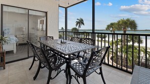 Ein Balkon mit Tisch und Stühlen, einem Deckenventilator und Blick aufs Meer.