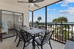 Ein Balkon mit Tisch und Stühlen, einem Deckenventilator und Blick aufs Meer.