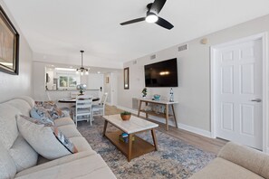 A modern living room with a sofa, coffee table, and a TV mounted on the wall. - ⛱️Beautiful Gulf Views | Easy Beach Access | Gulf Haven-Carlos Pointe #222⛱️ (Fort Myers Beach)