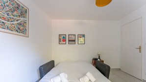 Et hotelværelse med en seng, to lænestole, et natbord og en dør.