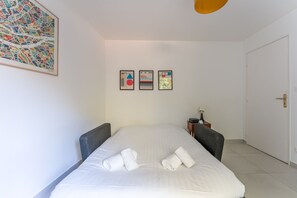 Ein Hotelzimmer mit einem Bett, zwei Sesseln, einem Nachttisch und einer Tür.