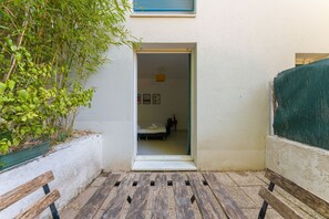 Une petite pièce avec un lit, une fenêtre et une porte donnant sur un balcon.