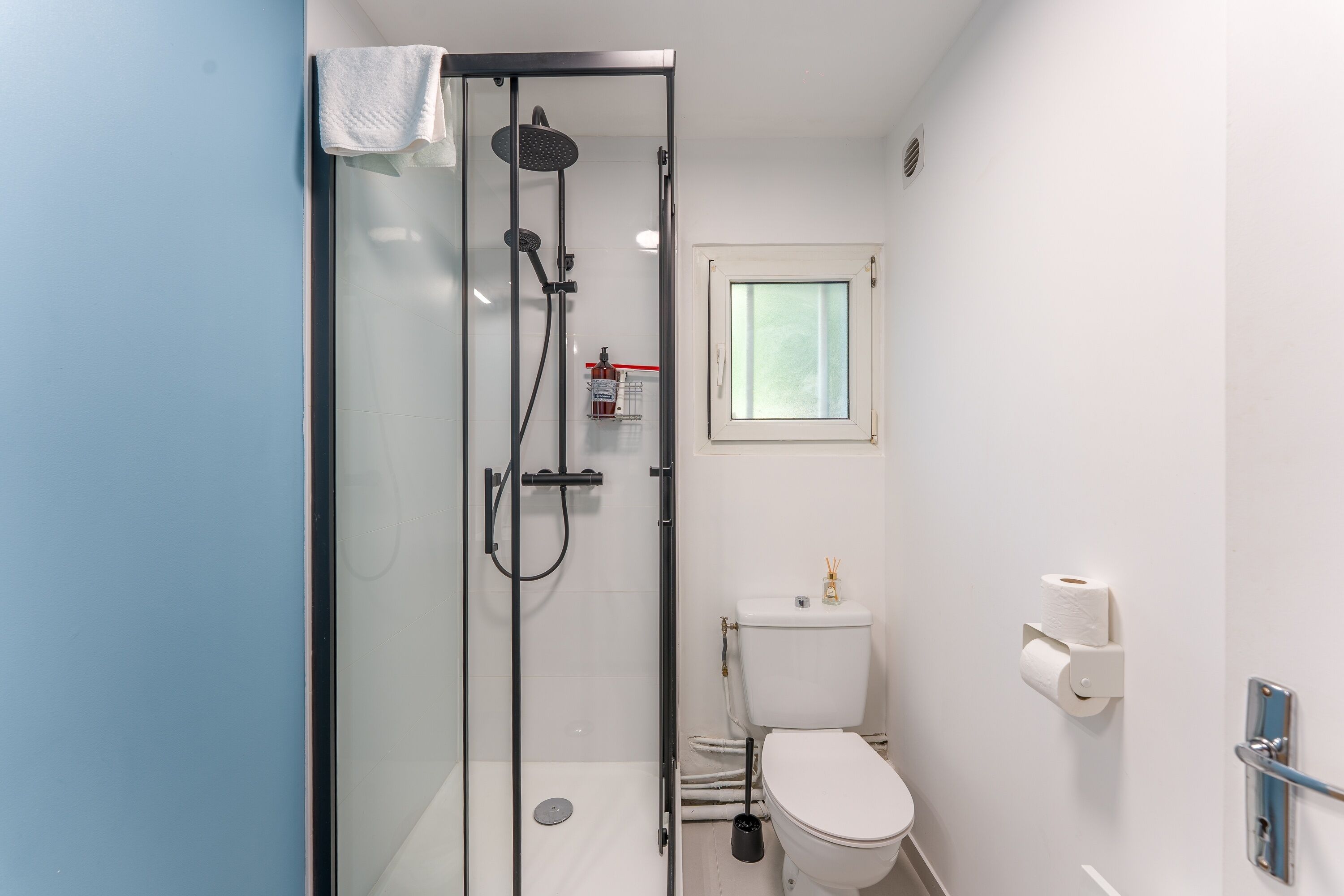 Ein modernes Badezimmer mit einer Duschkabine, einer Toilette und einem Fenster.
