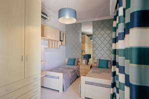 A bedroom with two beds, a wardrobe, a mirror, and a hanging light fixture. - Luxury Duplex with Jacuzzi, Stunning Views (Saint Julian's)