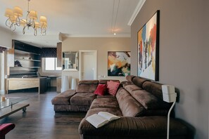 Ein modernes Wohnzimmer mit einem Ecksofa, einem Glastisch und einer Kronleuchter.