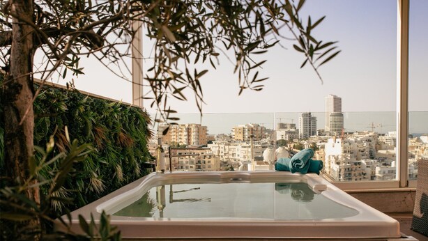 Un jacuzzi con vista a la ciudad, rodeado de vegetación y cielo despejado.