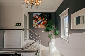 Eine Treppe mit Metallgeländer, ein Blumentopf, ein Gemälde und ein Fenster mit Jalousien.