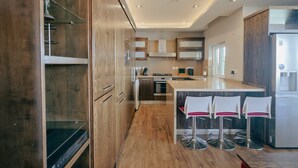 Una cocina moderna con armarios de madera, electrodomésticos de acero inoxidable y una barra con taburetes.
