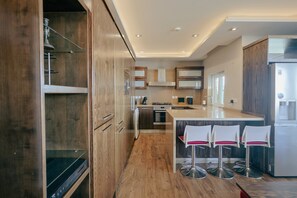Eine moderne Küche mit Holzausstattung, Edelstahlgeräten und einer Bar mit Barhocker.