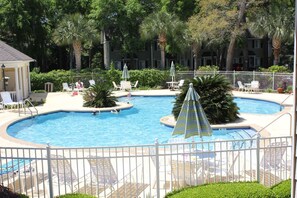 A swimming pool with lounge chairs and umbrellas, surrounded by palm trees and a white fence. - 2br/2ba Ocean Walk condo for monthly rentals - December through March (Saint Simons Islandd)