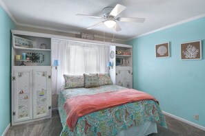 A bedroom with a bed, a ceiling fan, a window with curtains, and decorative items on shelves. - 2br/2ba Ocean Walk condo for monthly rentals - December through March (Saint Simons Islandd)