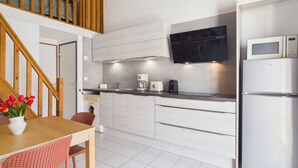 A modern kitchen with a built-in microwave, a stainless steel refrigerator, and a wooden staircase. - La Maison L'île Bleue - À 700 m de la plage (Gruissan)