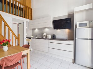 Eine moderne Küche mit integriertem Mikrowellenherd, einem Edelstahlkühlschrank und einer Holztreppe.