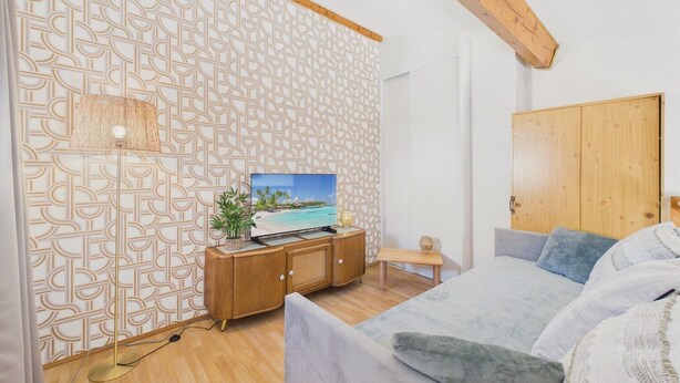 A bedroom with a wooden ceiling, a patterned wall, a bed, a TV, and a wooden wardrobe. - La Maison L'île Bleue - À 700 m de la plage (Gruissan)