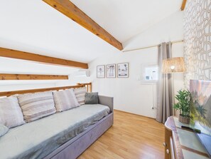 Ein modernes Wohnzimmer mit einer Couch, Holzbalken, einem Fenster und Wandbildern.