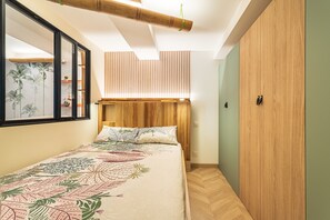 A bedroom with a bed, wooden headboard, a mirror, and a wardrobe. - Suite Jungle Premium - Studio climatisé (Toulon)