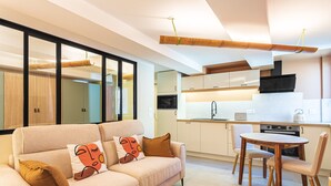 A modern living room with a sofa, a dining table, and a kitchen in the background. - Suite Jungle Premium - Studio climatisé (Toulon)
