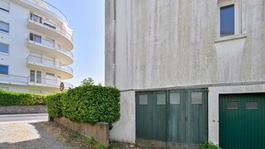 Ein Gebäude mit grüner Tür, weißer Wand und einer Hecke.