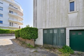Ein Gebäude mit grüner Tür, weißer Wand und einer Hecke.