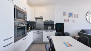 Eine kompakte Küche mit modernen Geräten, ein Essbereich mit Tisch und Stühlen sowie eine kleine Sitzecke mit einer Couch.