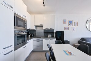 Eine kompakte Küche mit modernen Geräten, ein Essbereich mit Tisch und Stühlen sowie eine kleine Sitzecke mit einer Couch.