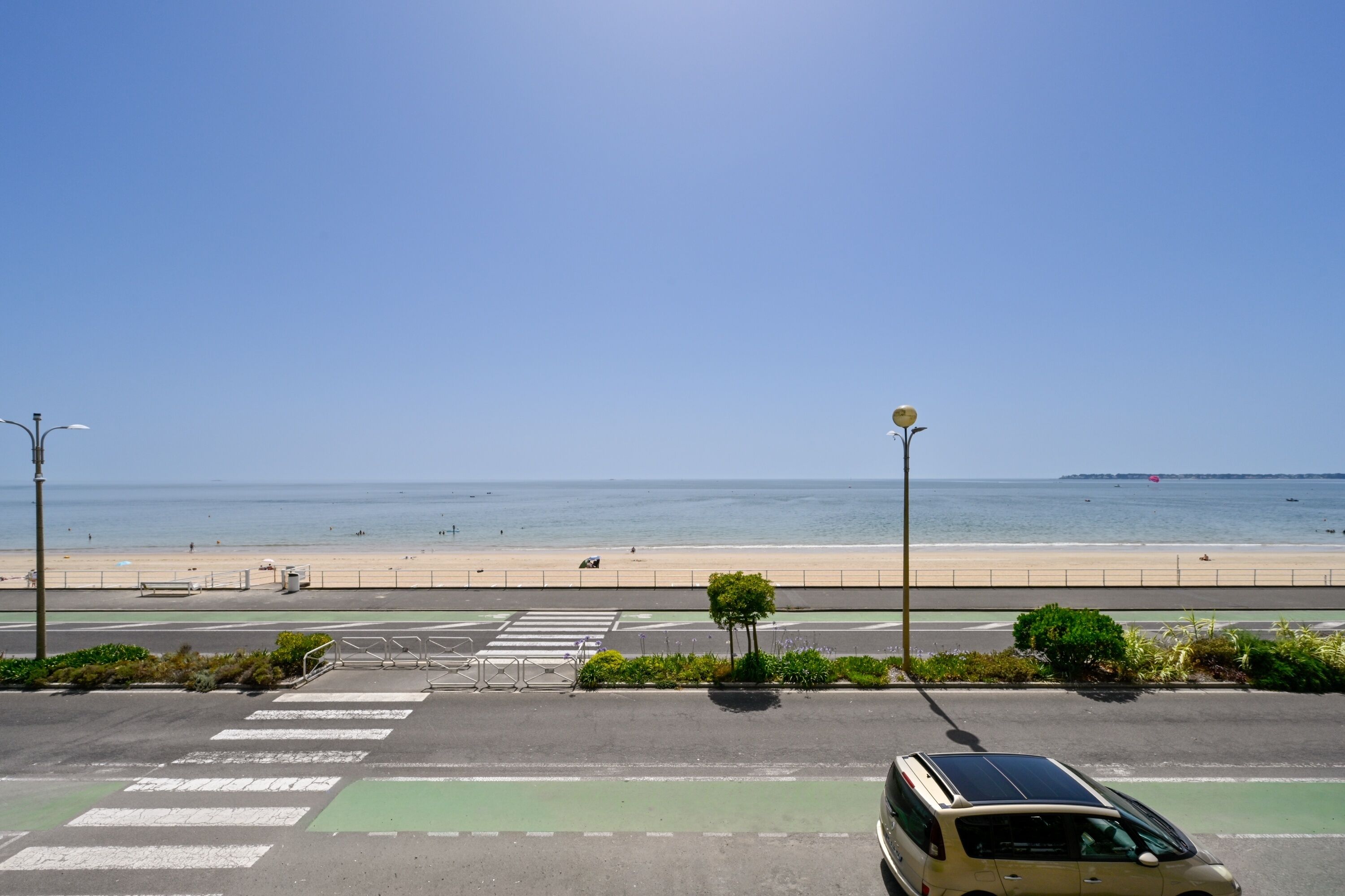 Eine Straße führt zu einem Strand, wo ein Van am Straßenrand geparkt ist.