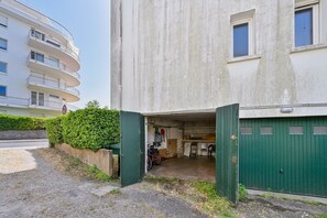 A multi-story residential building with a green gate, a bicycle, and a small storage area. - La Résidence - Appt avec balcon et vue mer (La Baule)