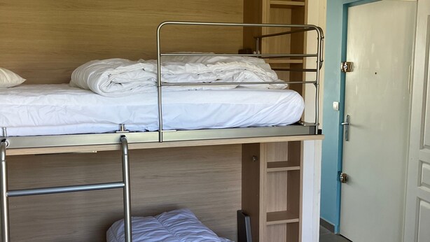 Ein Schlafraum mit Etagenbetten, einem Holzschrank und einer Tür.