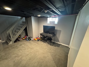 A room with a desk, a chair, a television, and a staircase. - Family Vacation house (Redford)