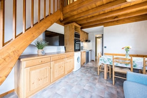 Une cuisine avec des meubles en bois, un lave-linge et un coin repas comprenant une table et des chaises.