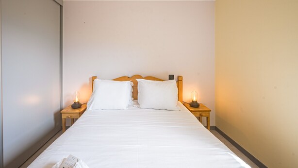 Ein Einzelbett mit weißen Bettwäsche, zwei Nachttische mit Lampen und ein Holz-Kopfbrett.