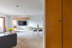A modern kitchen with a flat-screen TV, wooden cabinets, and a dining area with a table and chairs. - Le Havre de Mandelieu - Appt à 20min de Cannes (Mandelieu-la-Napoule)