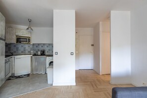 A modern kitchen with a microwave, toaster, and kettle, a washing machine, and a dining area with a bench. - Le Havre de Mandelieu - Appt à 20min de Cannes (Mandelieu-la-Napoule)