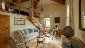 A spacious living room with a staircase, wooden beams, a chandelier, and a large vase. - Pézenas Mill (Pézenas)