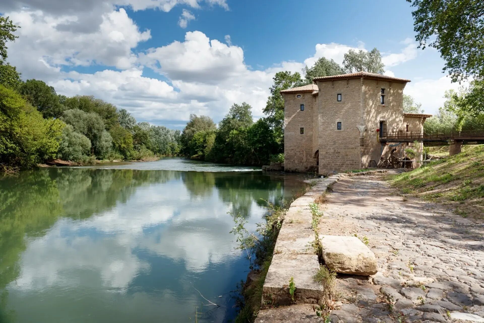 Ein Steinhaus am ruhigen Fluss, umgeben von üppigem Grün.