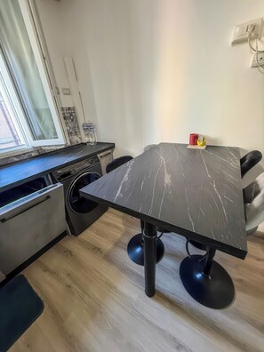 Una cocina moderna con lavadora incorporada, una mesa de comedor con cubierta de mármol y un ventanal con vistas.