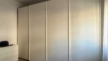 Quarto com guarda-roupa, mesa de cabeceira e colcha azul.