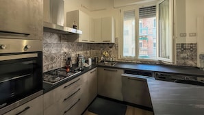 Uma cozinha moderna com eletrodomésticos de aço inoxidável, máquina de lavar louça e janela com vista para um edifício.