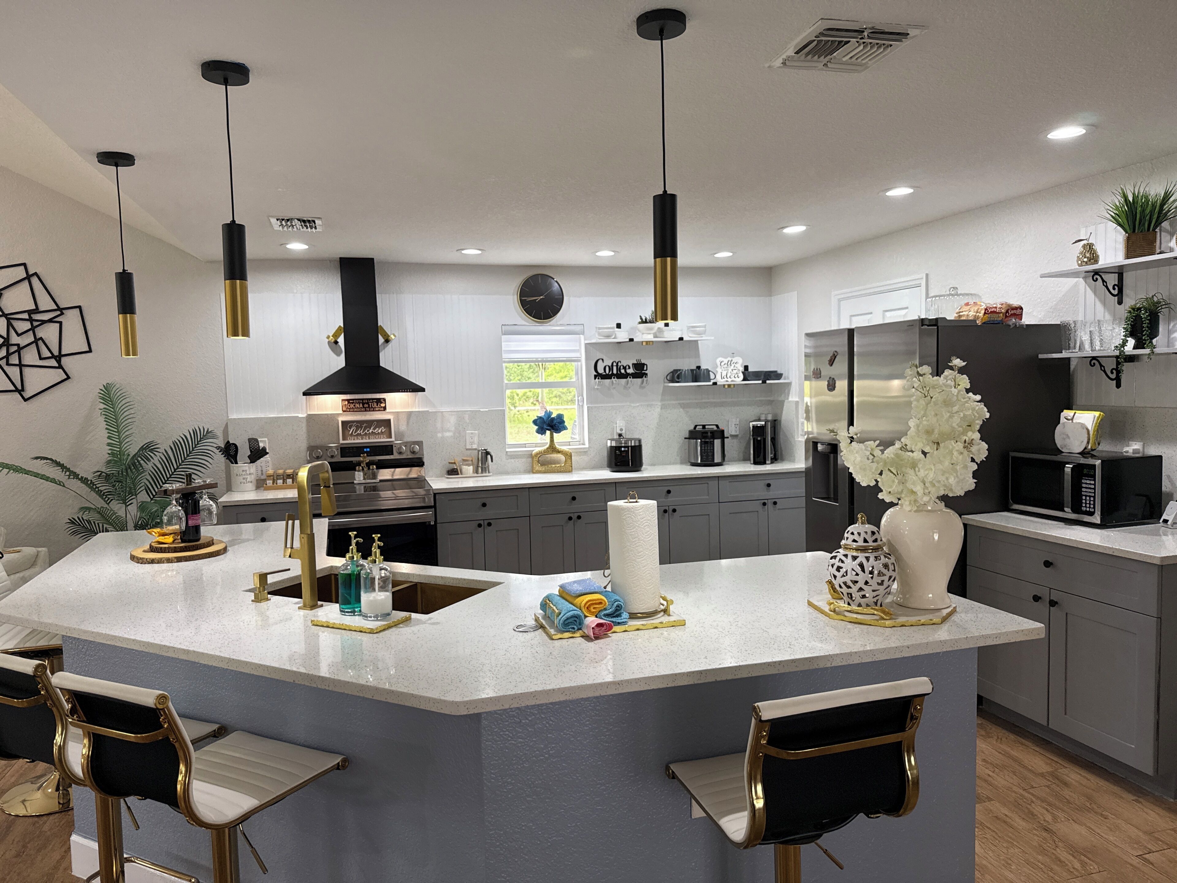 A modern kitchen with a central island, bar stools, pendant lighting, and built-in appliances.