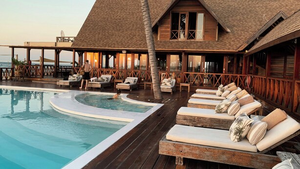 A wooden building with a pool, lounge chairs, and a palm tree. - NovaStar Test Hotel xhcbnh (Seattle)