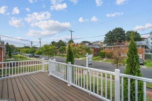 Um bairro residencial com casas, uma rua e um deck de madeira com guarda-corpo branco.