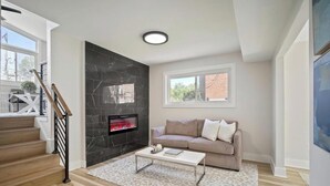 Una sala de estar moderna con chimenea, un sofá, una mesa de centro y una escalera.